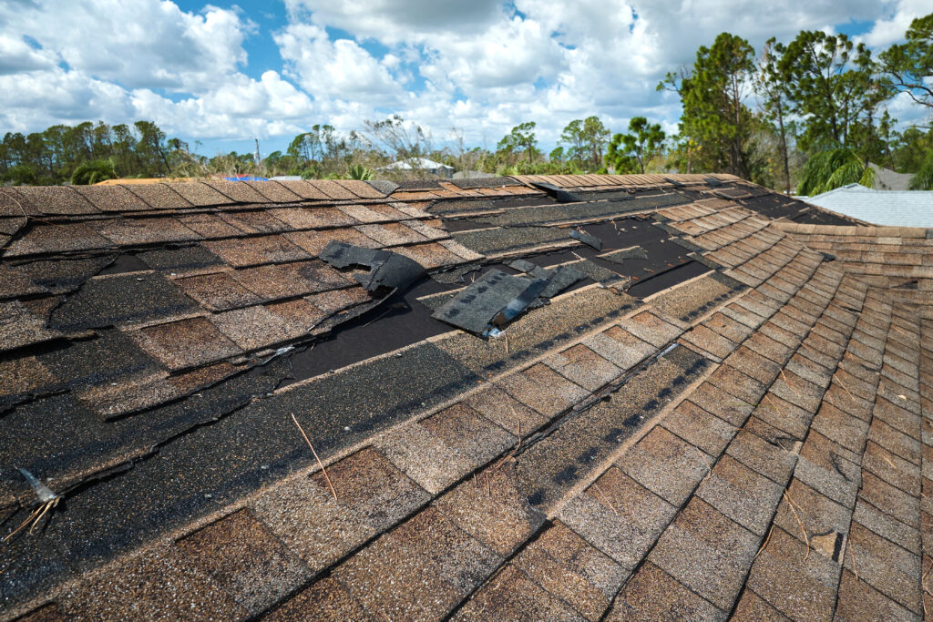 Visible signs of damage on a roof, including broken shingles and dented flashing.
